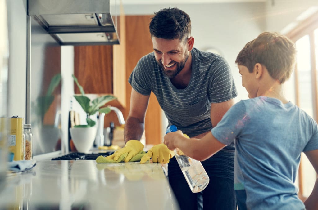 Father and son cleaning the kitchen counter.
