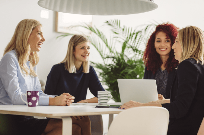 women sitting in a meeting with a laptop