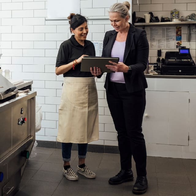 food services employees looking at a tablet at work