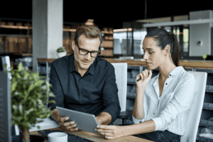 Male and female coworkers looking at a laptop.