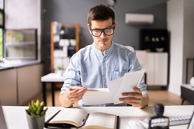 man looking at envelopes at desk at work