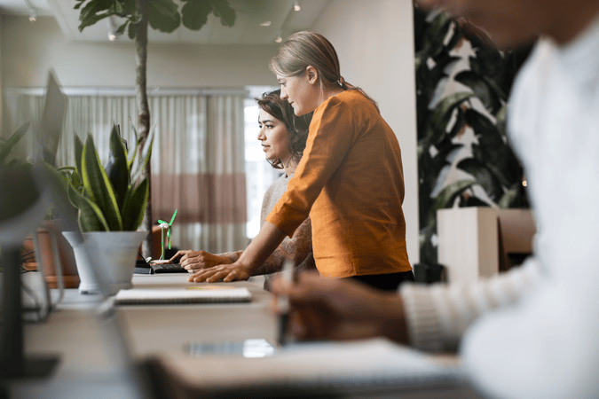 two women working at a desk together in an office.